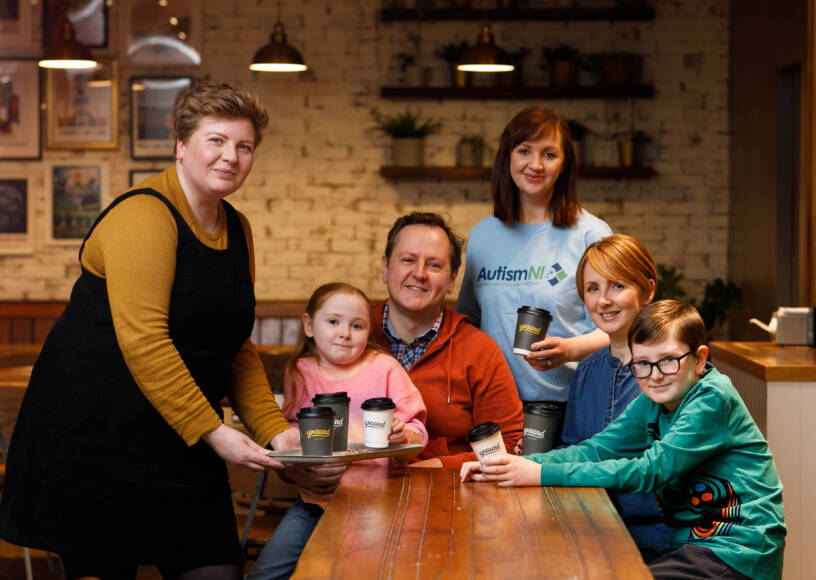 A group of people pose in a coffee shop and smile