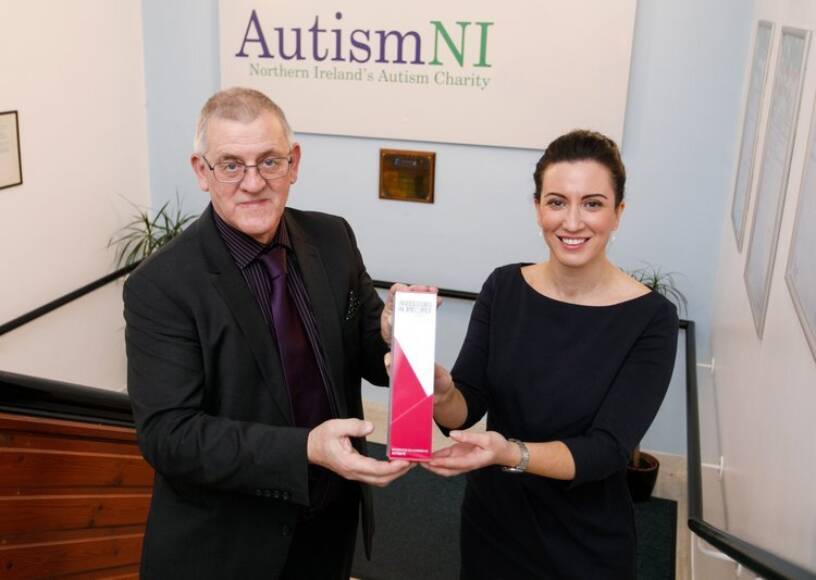 Two people smile and pose with an award