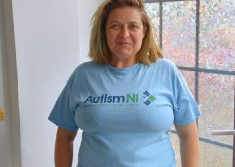 A woman smiling and wearing an Autism NI T-shirt