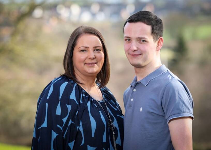 A mother and son smile and pose together outdoors