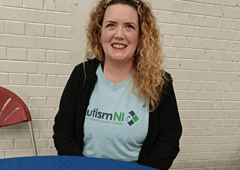 A woman smiling and wearing an Autism NI T-shirt