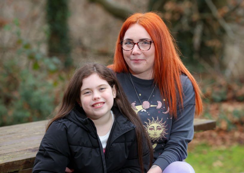 Mother and daughter smile together while sitting outside at a picnic bench