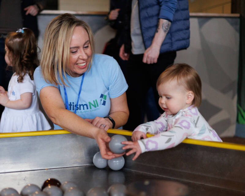 Autism NI member smiling and playing with a small child