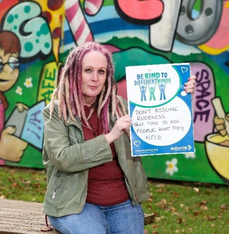 Autism NI member holding a 'Be kind to different minds' poster