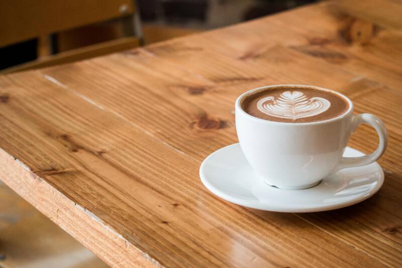 A coffee cup with a foam pattern on a wooden table