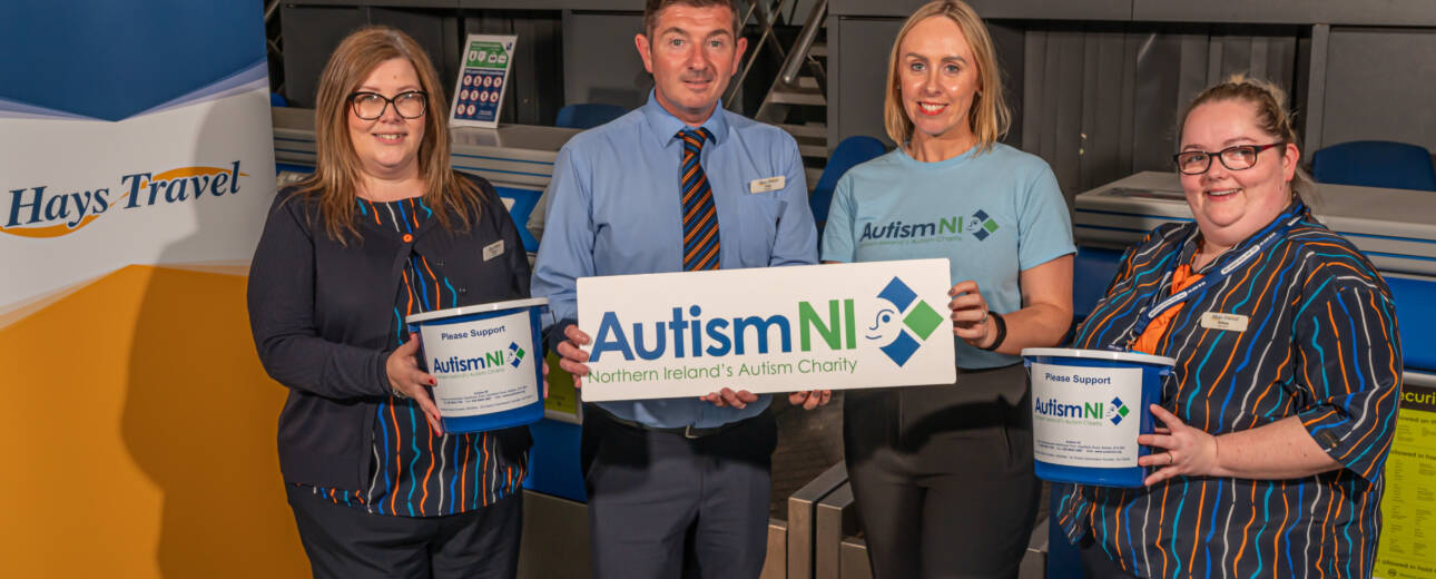 A group of people hold an Autism NI sign and donation buckets