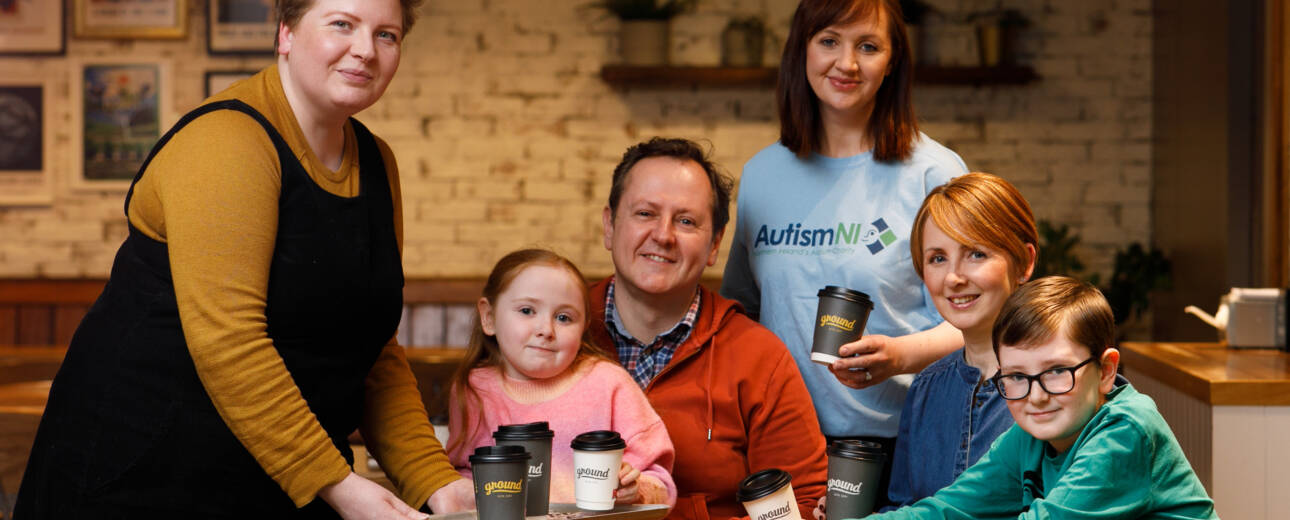 A group of people pose in a coffee shop and smile