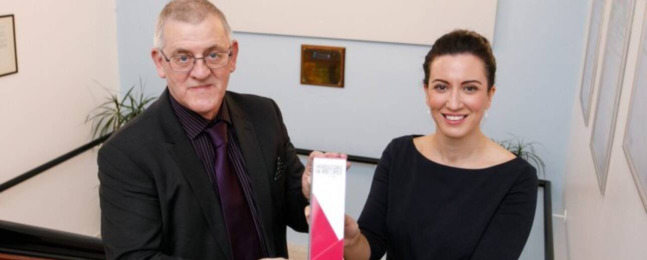 Two people smile and pose with an award