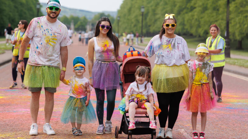 A family stand on the road and are painted with colour powder from taking part in a fundraising challenge from Autism NI.