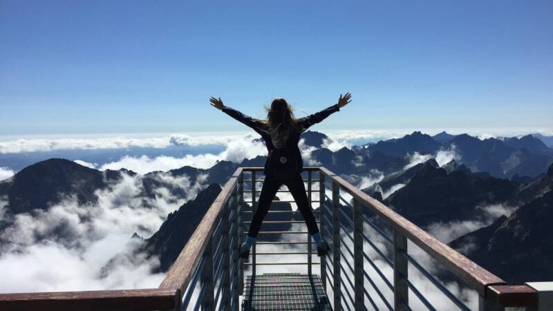 A person standing on a walkway in a mountainous landscape