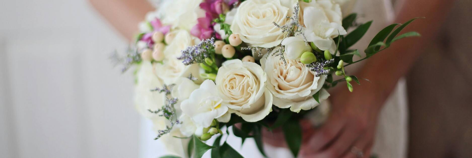 A bride holds a bouquet in front of her torso