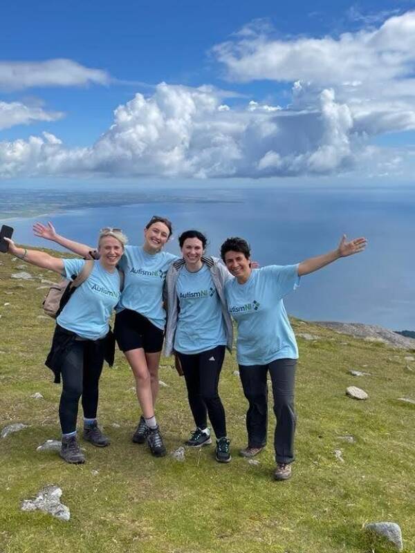 A group of Autism NI members smiling and posing in the Mourne Mountains
