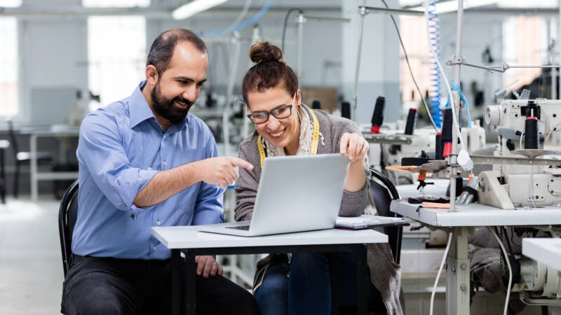 Autistic Adult Resources icon: The picture shows two employees sitting at a table looking at a laptop screen.