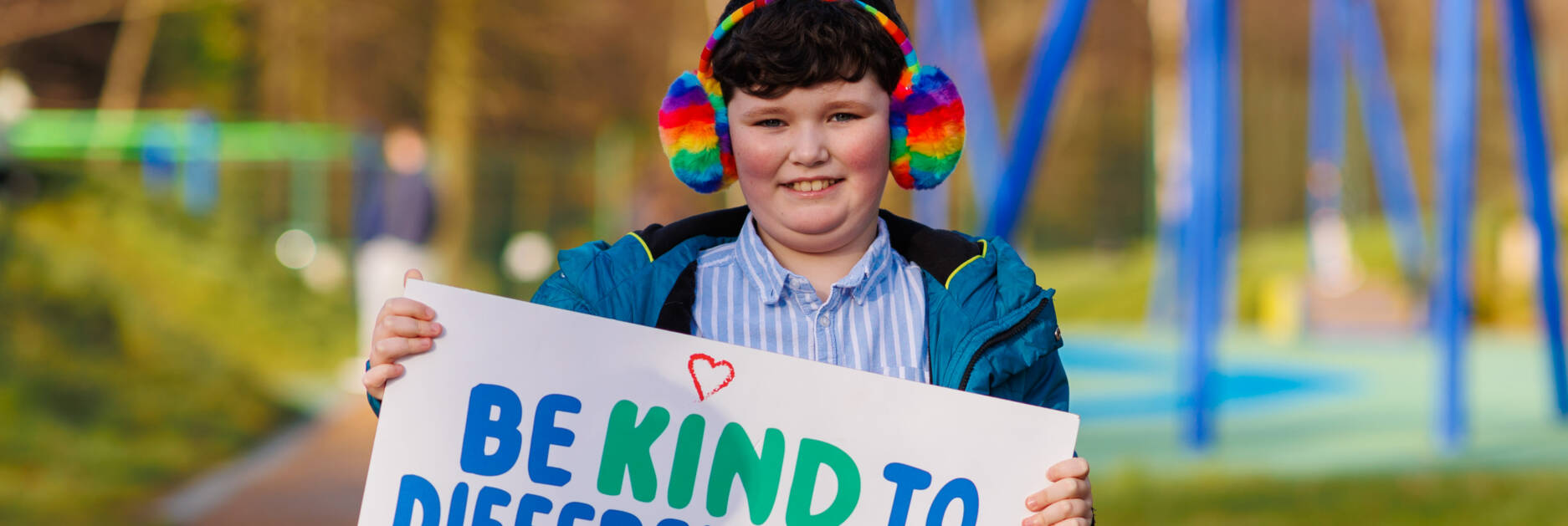 Autism NI member holding a 'Be kind to different minds' poster