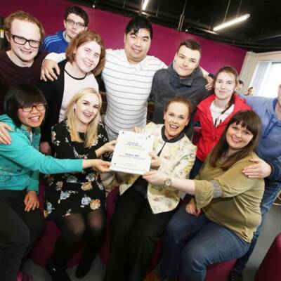 A group of people smile and pose together with an Autism NI impact award