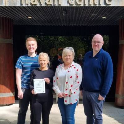 Several people posing with an impact award beneath 'Navan centre' signage