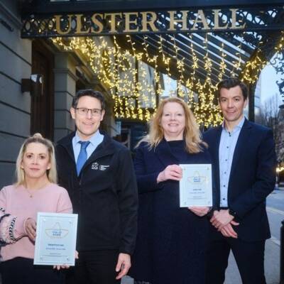 A group of people pose with impact awards outside The Ulster Hall