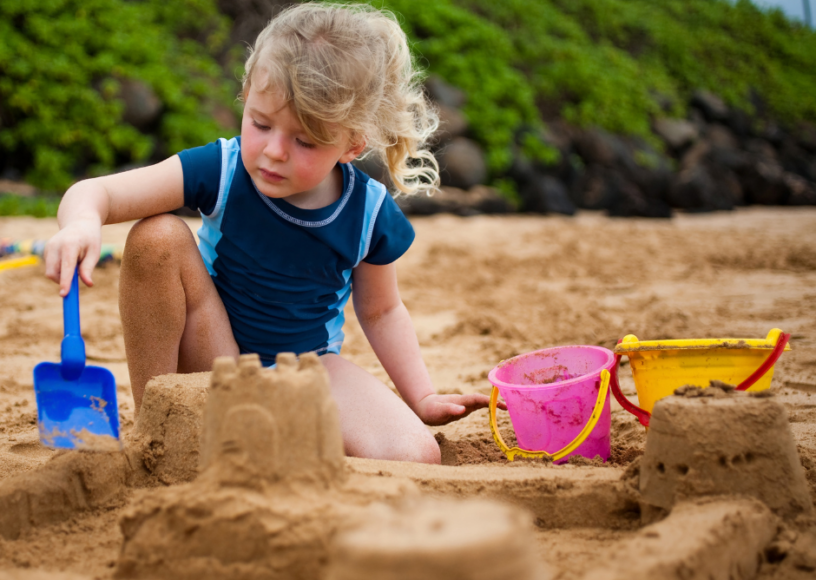 Child playing on the beach, making sandcastles in the Summer Break