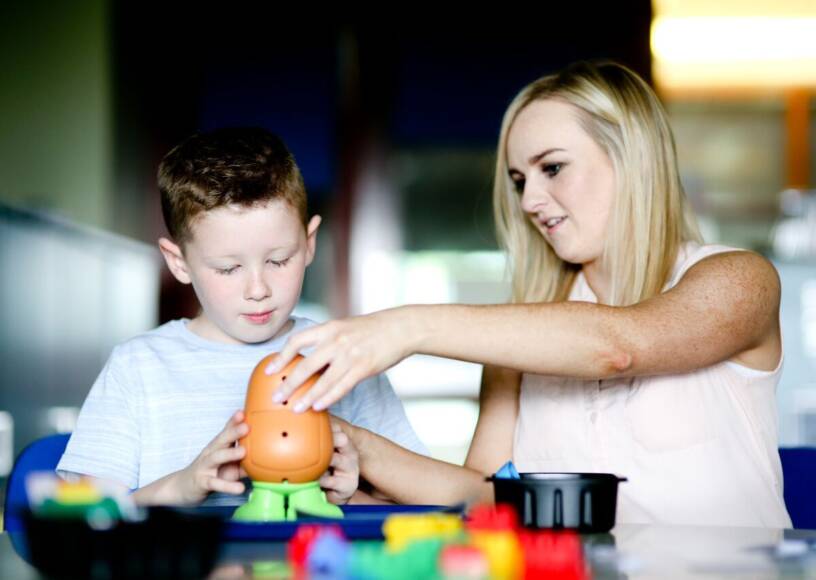 A child and Adult playing together with Mr Potato Head, with duplo blocks in the foreground.