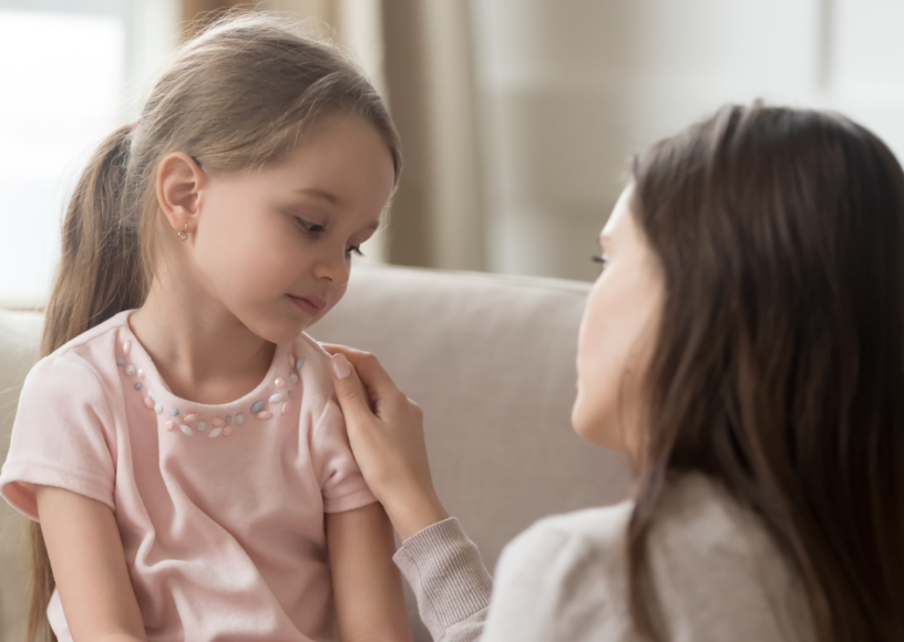 Shy or nerVous child being supported by her Mum.