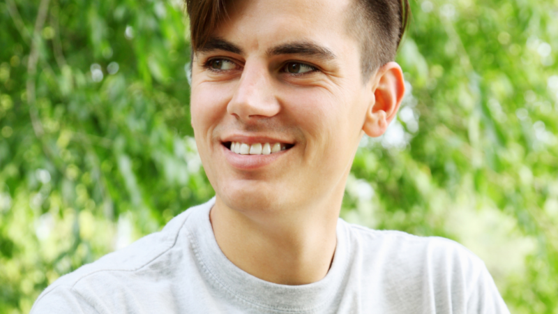 An adult male looking to right, smiling and content.