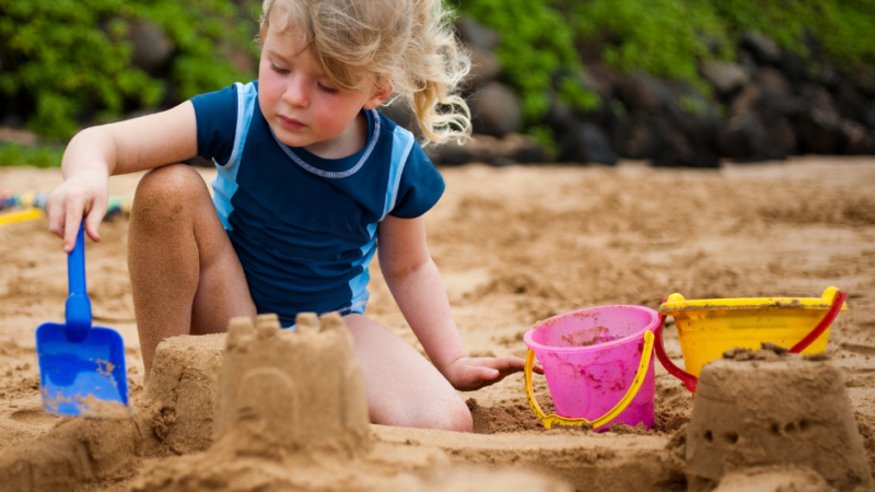 Child playing on the beach, making sandcastles in the Summer Break