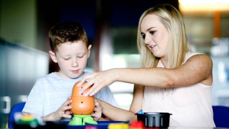 A child and Adult playing together with Mr Potato Head, with duplo blocks in the foreground.