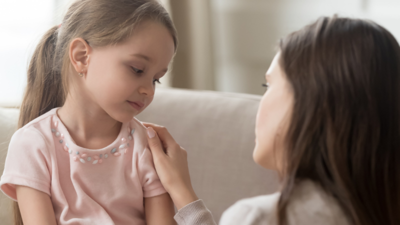 Shy or nerVous child being supported by her Mum.